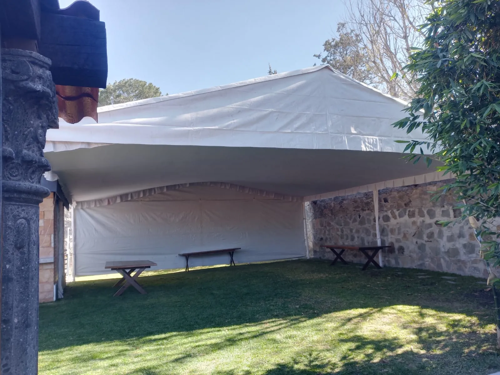 Carpa estructural fija cubriendo el patio de una finca con muro de piedra