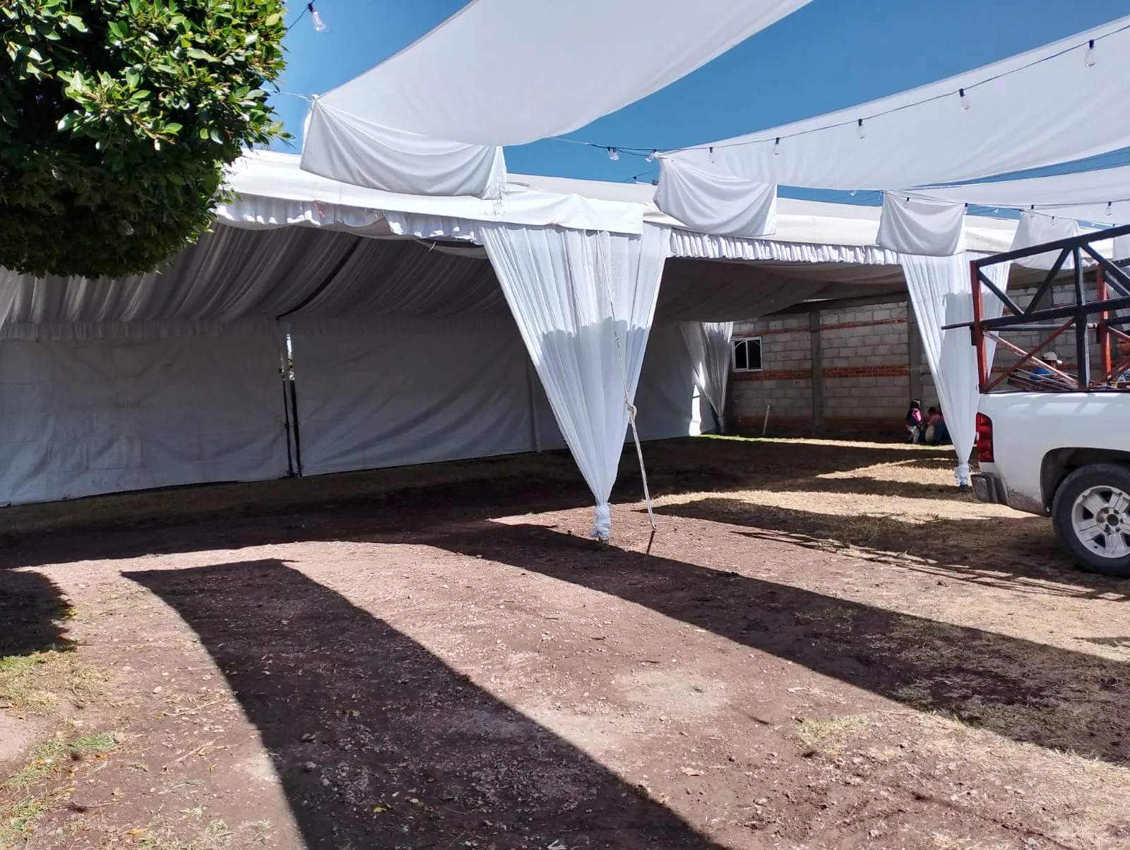 Montaje de una carpa con drapeado sobre el patio de tierra de una propiedad